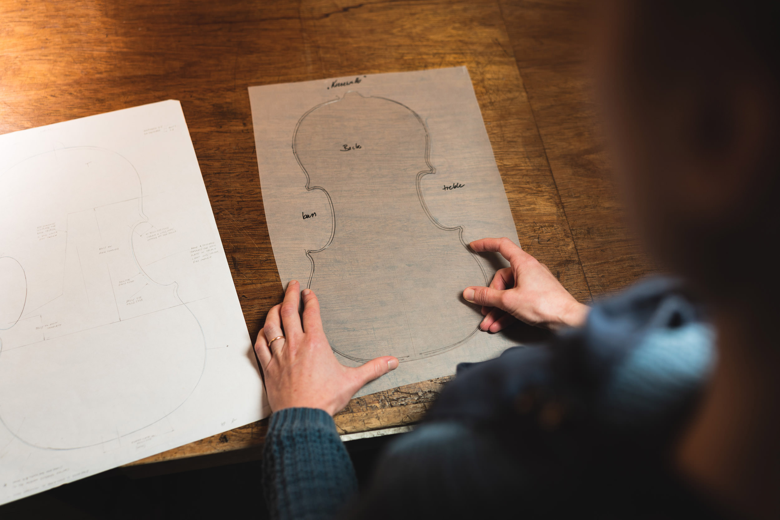 Artisan working with template in violin making workshop

